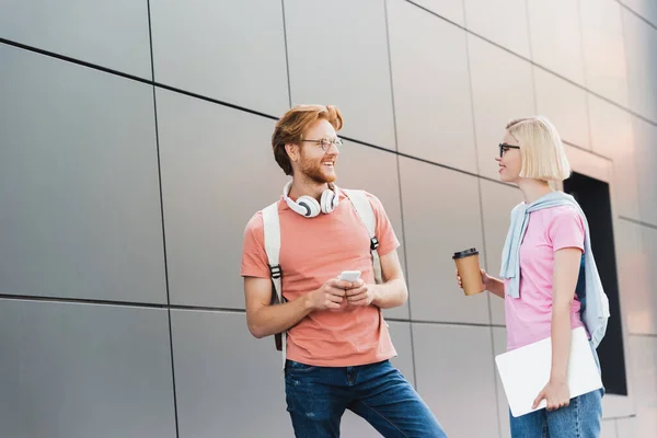 Blonde Student Holding Paper Cup Laptop While Looking Redhead Friend — Stock Photo, Image