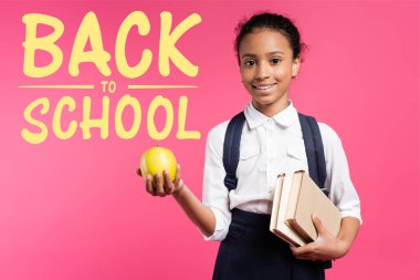 Sırt çantası ve elmalı Afro-Amerikan okul kızı. Okulun yanında pembe harflerle yazılmış.