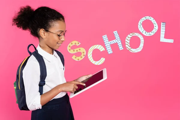 アフリカ系アメリカ人の女子高生がピンクの学校のレタリングの近くのデジタルタブレットを使って — ストック写真