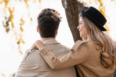 blonde woman in hat touching and looking at boyfriend outside clipart
