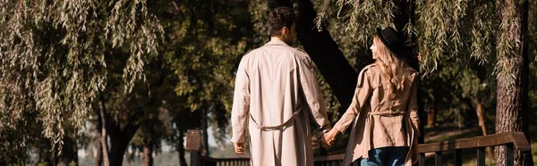 Gambar Horisontal Pasangan Dalam Mantel Parit Berpegangan Tangan Dan Berjalan — Stok Foto