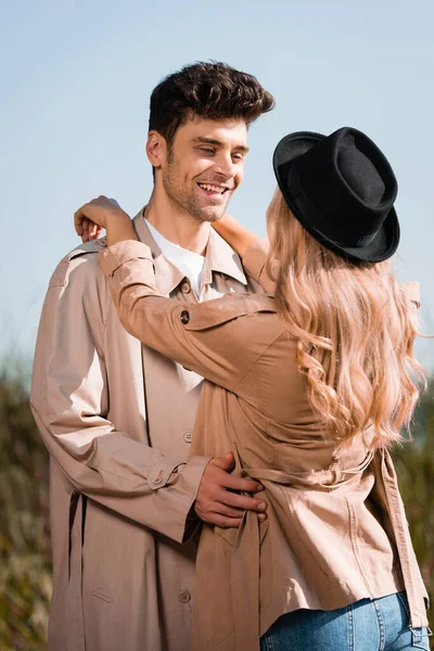 ブロンド女性で黒帽子抱擁男でトレンチコート — ストック写真