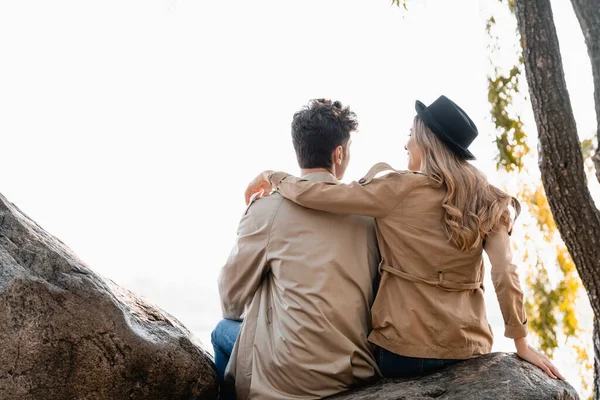 Blonde Woman Hat Hugging Man Trench Coat While Sitting Stones — Stock Photo, Image