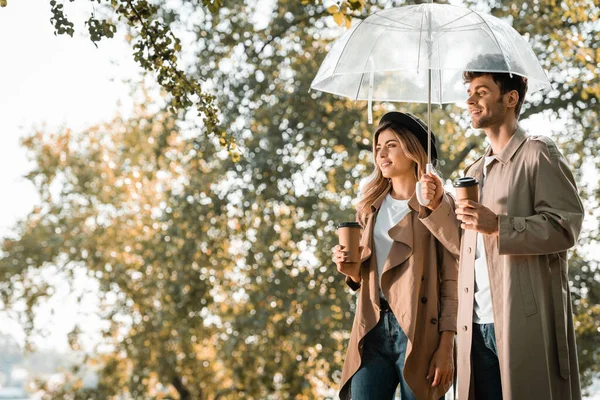 Coppia Trench Piedi Sotto Ombrello Possesso Tazze Carta Con Caffè — Foto Stock