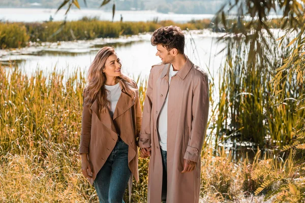 Pleased Woman Man Trench Coats Holding Hands Lake Autumnal Park — Stock Photo, Image