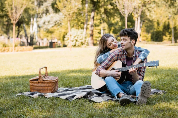 Woman Sitting Plaid Blanket Wicker Basket Touching Boyfriend Playing Acoustic — Stock Photo, Image