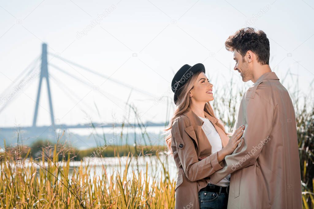 woman in hat and man embracing and looking at each other outside