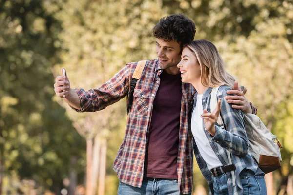 Man Neemt Selfie Met Vrouw Toont Vrede Teken Herfstpark — Stockfoto