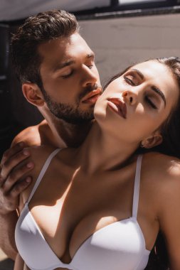 Üstsüz bir adam, genç ve seksi bir kadına dokunuyor.