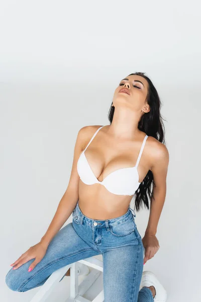 Sexy Woman Closed Eyes Jeans Bra Sitting Chair Isolated Grey — Stock Photo, Image