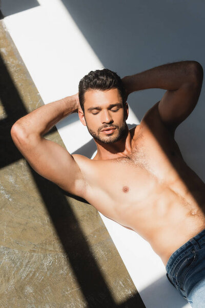 high angle view of shirtless man with closed eyes lying on white