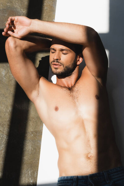 высокий угол обзора мускулистого и бородатого человека с закрытыми глазами, лежащими на белом