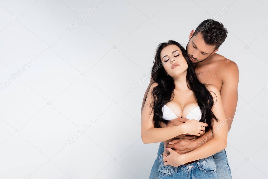 muscular man hugging sexy woman in white bra on grey
