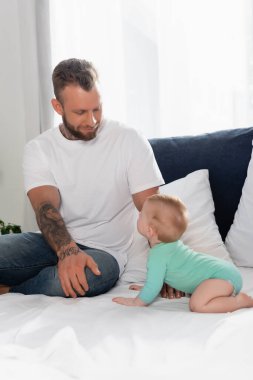 Baba ve bebeğin yatak odasında birbirlerine baktıkları seçici odaklanma.
