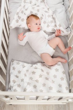 top view of infant boy in baby romper lying in crib clipart