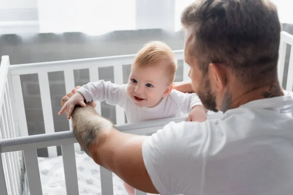 Back View Young Father Supporting Excited Infant Son Standing Crib — Stock Photo, Image