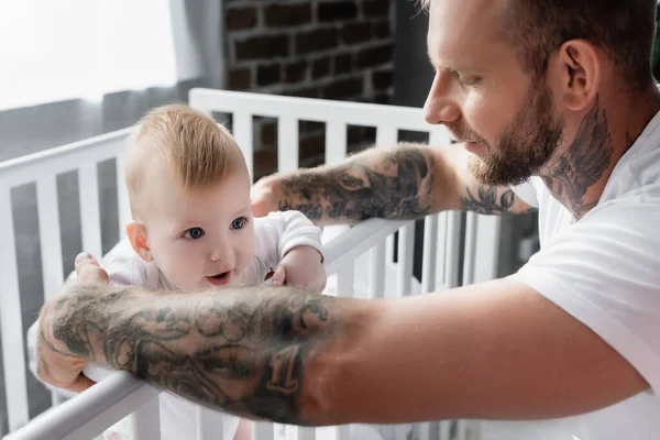 Selective Focus Tattooed Man Supporting Infant Child Standing Crib — Stock Photo, Image