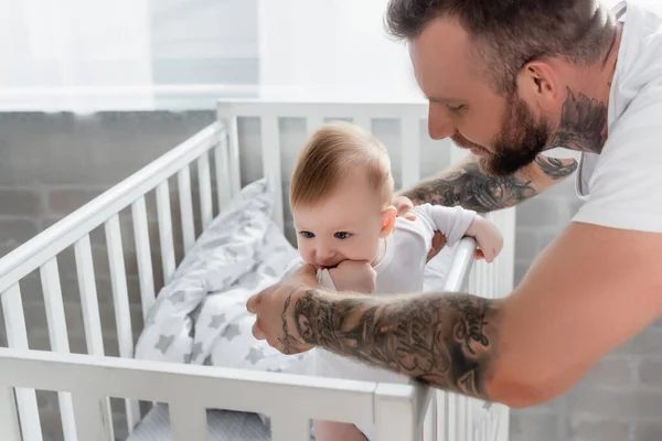 Fiatal Apa Támogatja Csecsemő Fiú Áll Bölcsőben Kéz Szájban — Stock Fotó