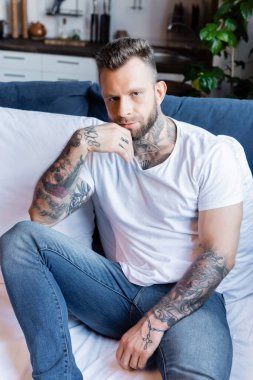 Kotlu ve beyaz tişörtlü adam kameraya bakarken el ele tutuşuyor.