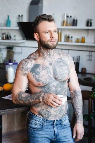 Junger Hemdlos Tätowierter Mann Schaut Weg Während Eine Tasse Kaffee — Stockfoto