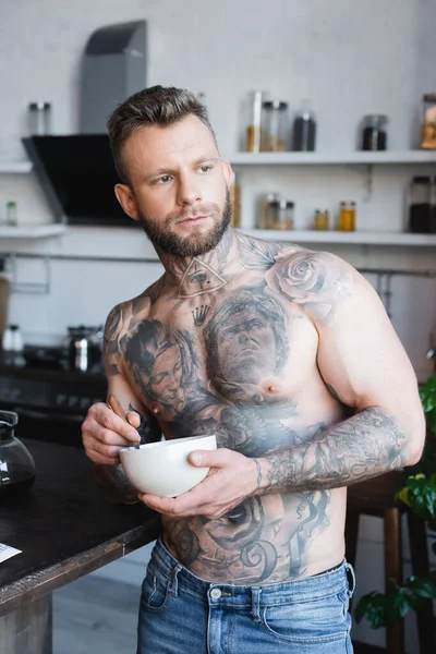 Kaslı Dövmeli Bir Adam Mutfakta Kahvaltıyla Kaseyi Tutarken Başka Tarafa — Stok fotoğraf