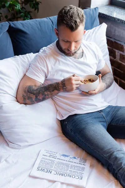 Young Tattooed Man Reading Economic News While Having Breakfast Bed — Stock Photo, Image