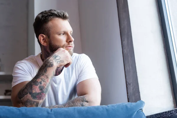 Pensativo Tatuado Homem Segurando Mão Perto Rosto Enquanto Olhando Para — Fotografia de Stock