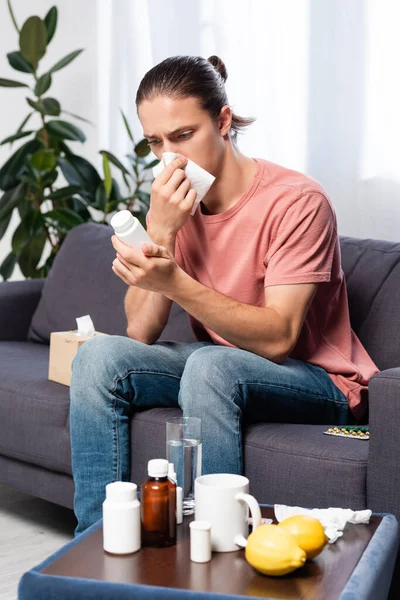 Kanepede Oturup Şişeyi Haplarla Tutarken Burnu Kağıt Peçeteyle Silen Hasta — Stok fotoğraf