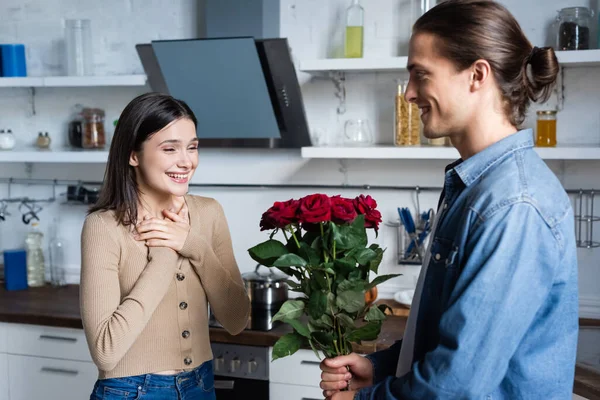 Homem Apresentando Rosas Para Mulher Satisfeita Mãos Dadas Perto Peito — Fotografia de Stock