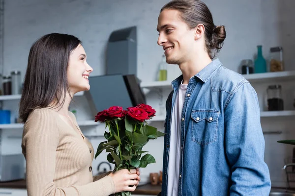 Mulher Alegre Olhando Para Homem Enquanto Segurando Buquê Rosas Cozinha — Fotografia de Stock