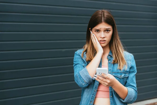 Rozrušený Teenager Dívá Kameru Zatímco Drží Smartphone Venku — Stock fotografie