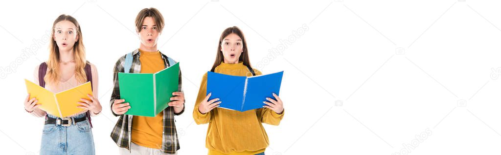 Panoramic shot of excited teenagers with backpacks holding notebooks isolated on white