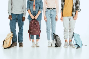 Gri arka planda sırt çantalı çoklu etnik gruptan gençlerin görüşü