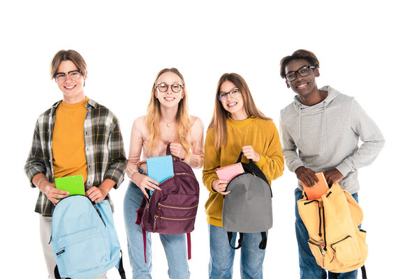 Smiling teenagers holding hooks and notebooks while looking at camera isolated on white