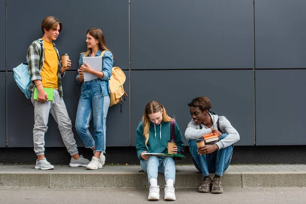 Lachende Multiculturele Tieners Met Koffie Naar Boeken Praten Buurt Van — Stockfoto