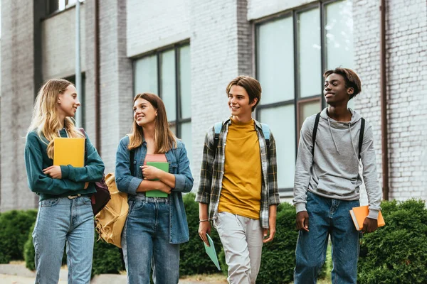 Adolescentes Multiétnicos Mirando Amigo Con Cuaderno Mientras Caminan Por Calle — Foto de Stock