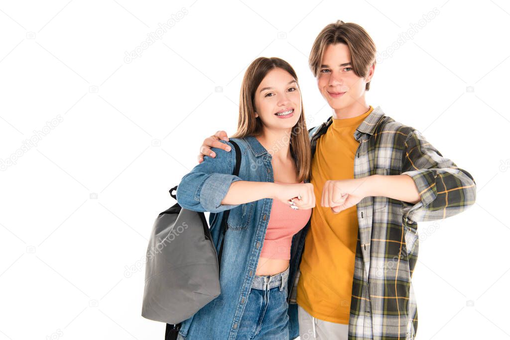 Positive teenagers hugging and doing fists bump isolated on white