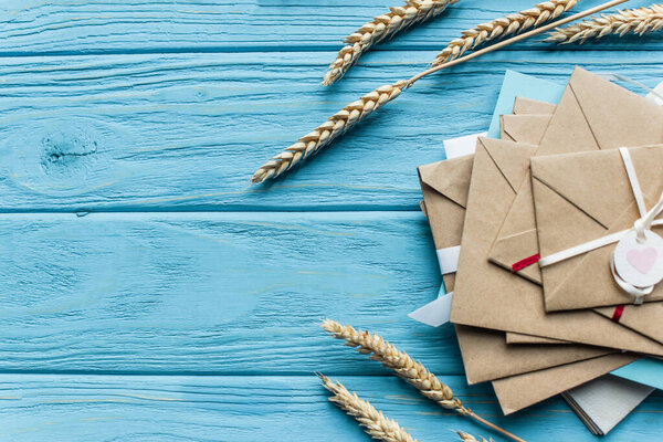 top view of wooden blue background with envelopes and wheat ears
