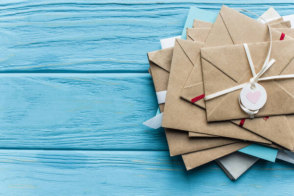 верхний вид деревянного синего фона с конвертами и сердцем