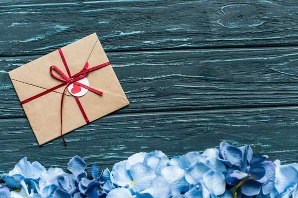 青い花の境界と封筒を持つ木製の緑の背景のトップビュー — ストック写真
