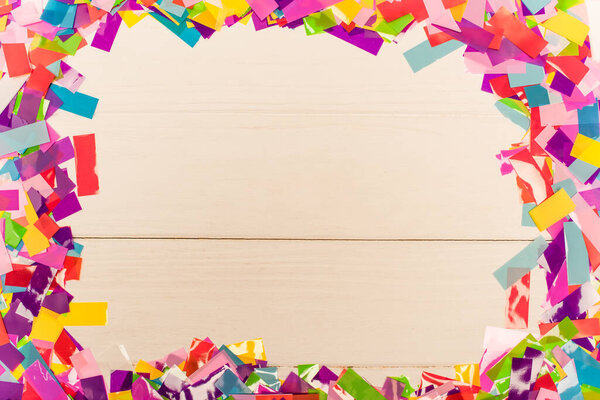 top view of colorful bright confetti frame on wooden background