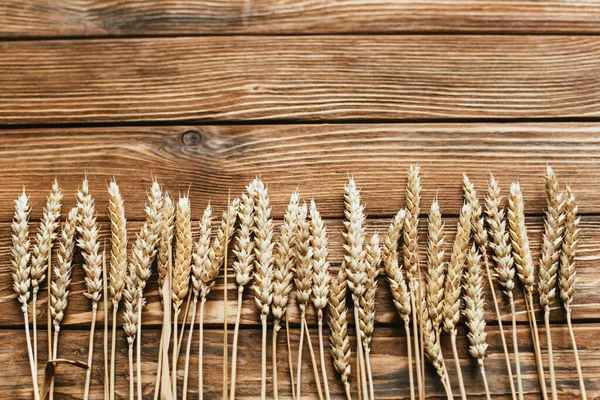 木製の背景にある小麦の耳の上からの眺め — ストック写真