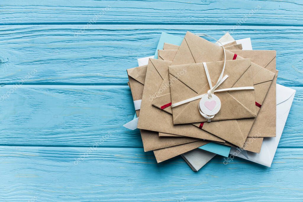 Top view of wooden blue background with envelopes and heart