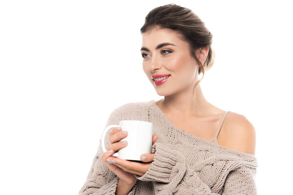 sensual woman in stylish knitted sweater holding cup of warm beverage isolated on white