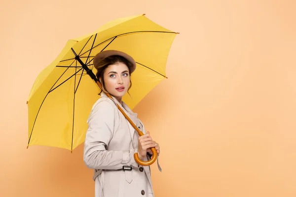 Elegant Woman Trench Coat Beret Looking Away Yellow Umbrella Peach — Stock Photo, Image