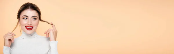 Горизонтальное Изображение Кокетливой Женщины Водолазке Касающейся Волос Изолированных Персике — стоковое фото
