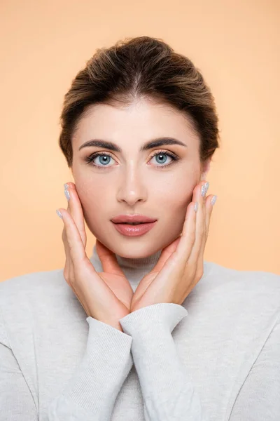 Stylish Woman Turtleneck Touching Face While Looking Camera Isolated Peach — Stock Photo, Image