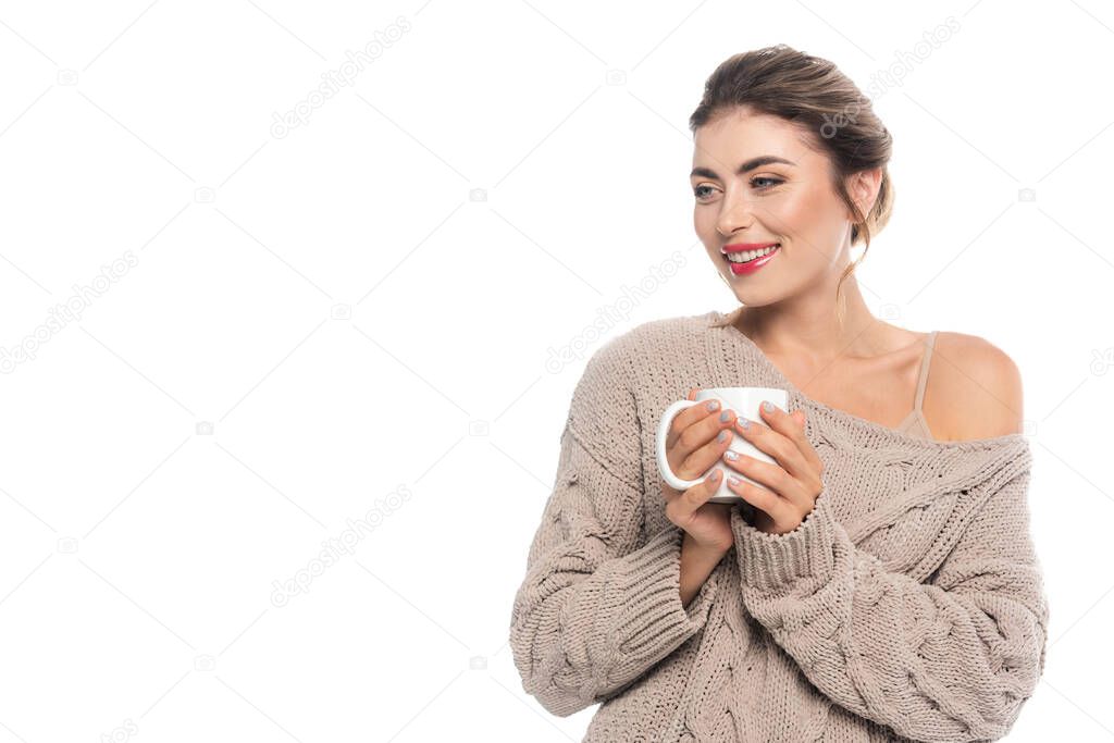 joyful woman in stylish knitted sweater holding cup of tea isolated on white