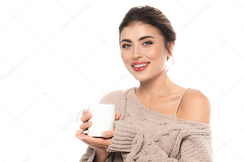 joyful woman in openwork sweater holding cup of warm drink isolated on white
