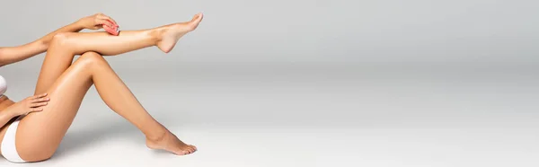 Beyaz Çamaşırlı Kadın Gri Pankartta Epilatorle Bacağını Tıraş Ediyor — Stok fotoğraf